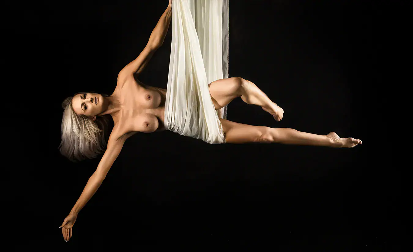 Aerial Fabric Artistic Nude Photography Artistic nude model suspended horizontally from white aerial fabric against a black background