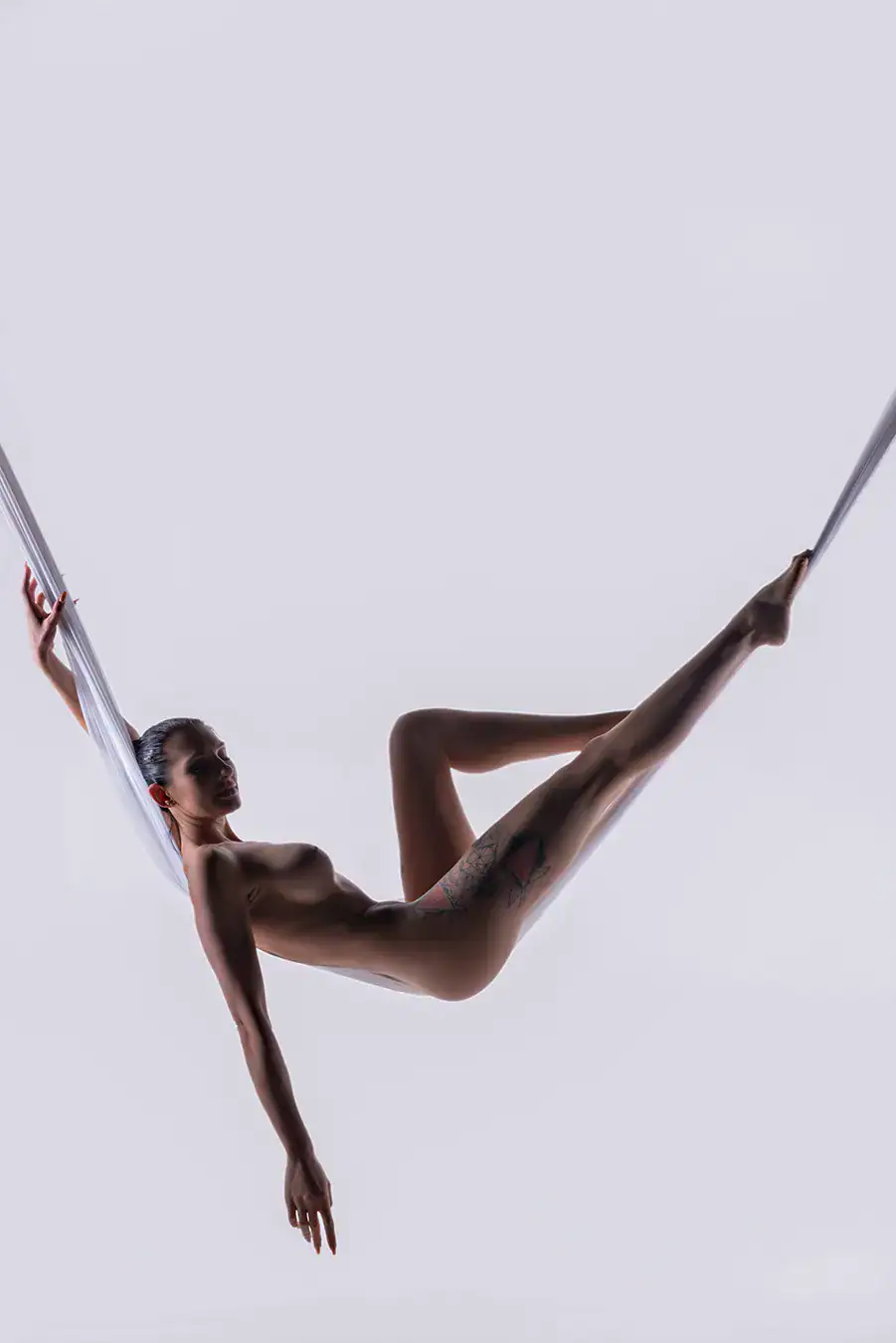 Aerial Silk Fine Art Photography Woman suspended from white aerial silks in a fine art studio portrait