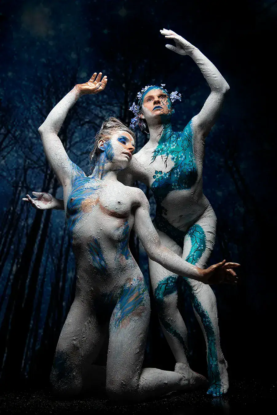 Forest Fairies Body Paint Concept Two women in an artistic forest fairies concept with blue and white body paint against a dark background