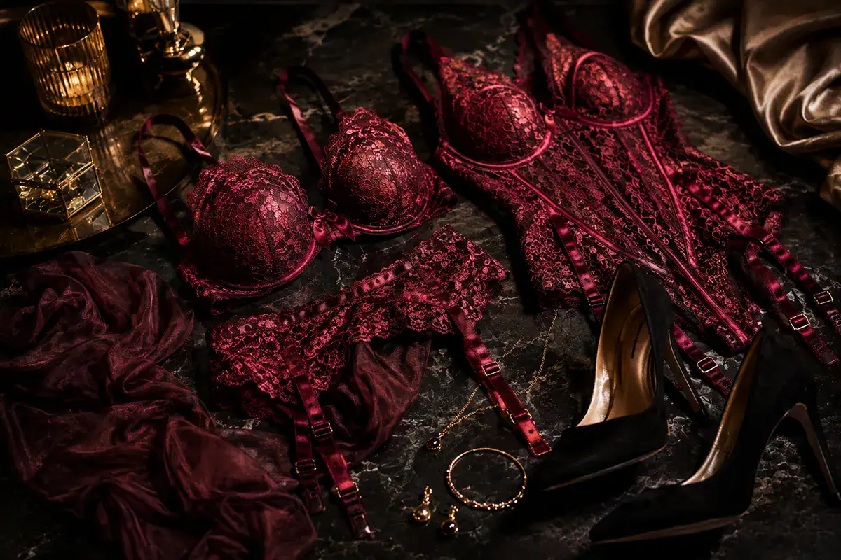 Burgundy lace lingerie, stockings, heels and jewellery arranged as boudoir photoshoot wardrobe ideas