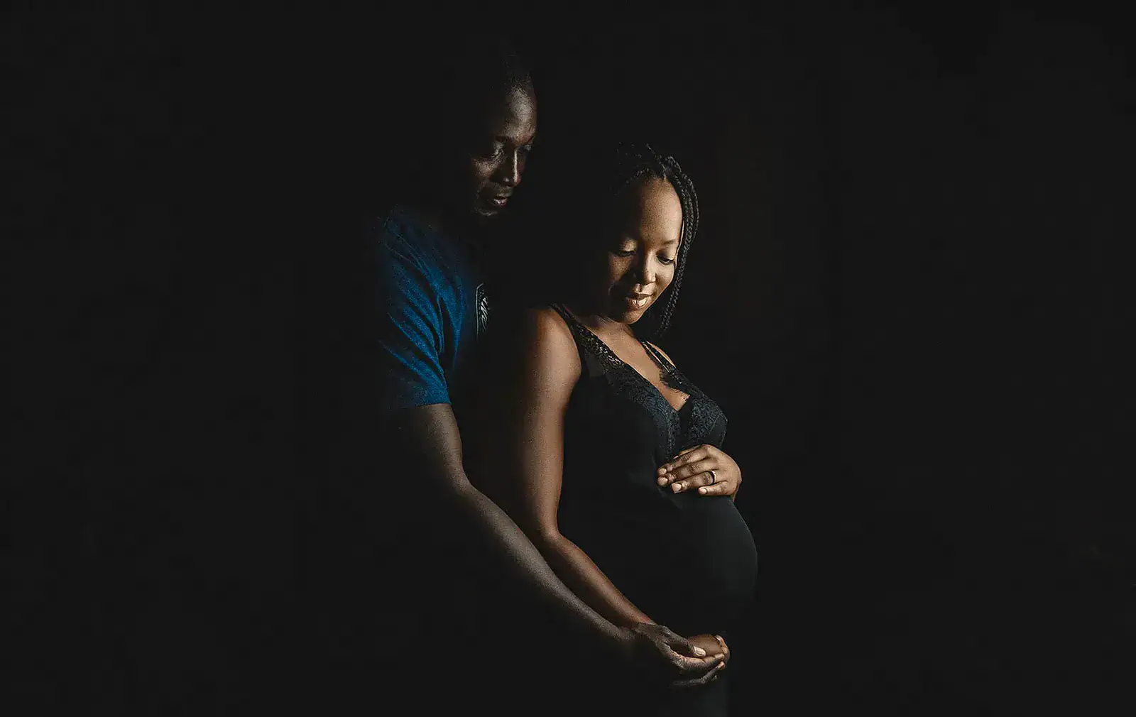 Low Key Pregnancy Portrait Pregnant woman photographed in dramatic low key lighting for an intimate pregnancy portrait