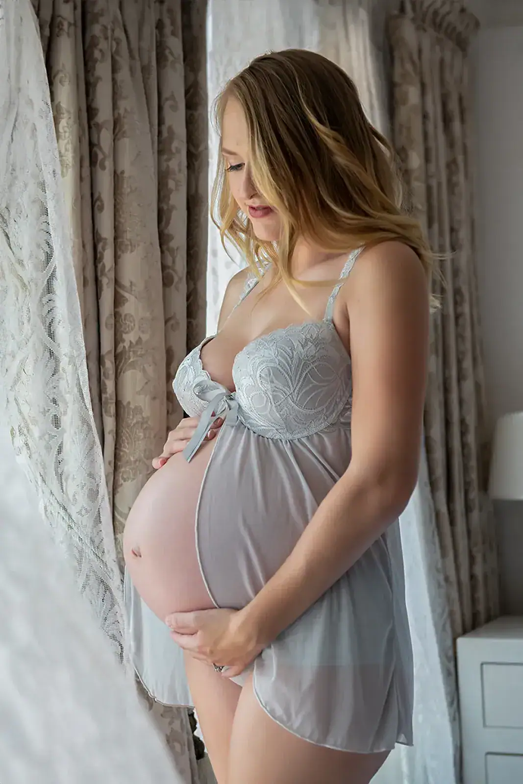 Natural Maternity Lingerie Portrait Pregnant woman in delicate lingerie beside a window during a soft natural light maternity photoshoot