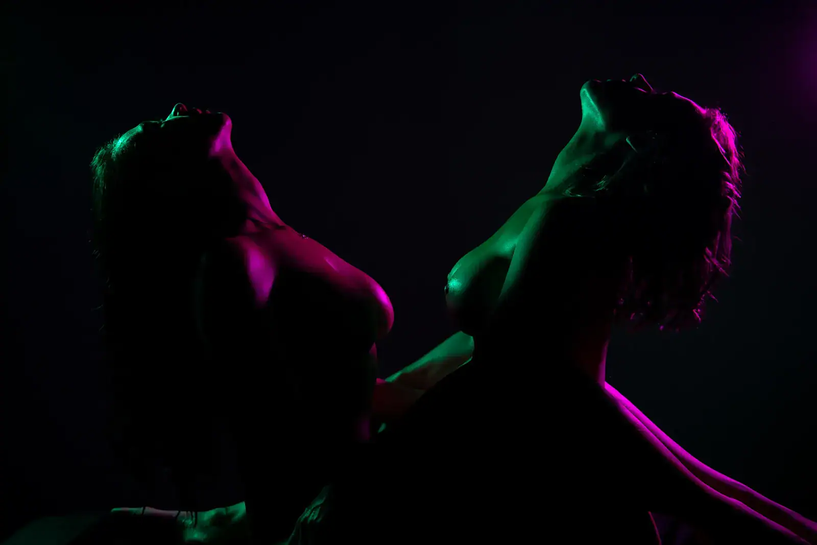 Neon Sensual Couple Silhouetted couple facing one another under vivid neon lighting in a sensual studio portrait.