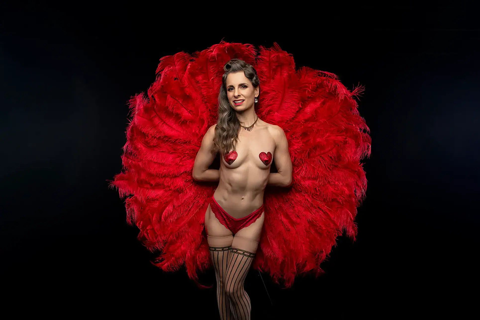 Red Feather Burlesque Conceptual Portrait Burlesque performer posed against an enormous circular red feather fan on a dark background
