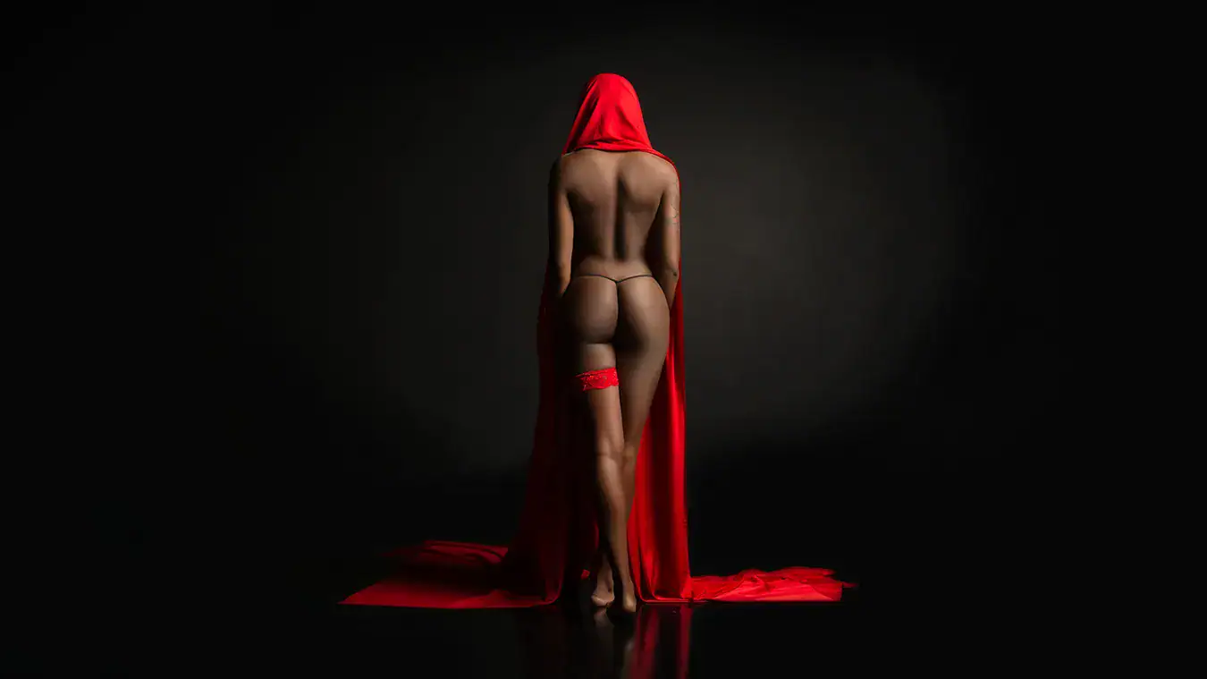 Red Hood Fine Art Nude Concept Fine art nude figure wearing a red hood with flowing red fabric against a dark studio background