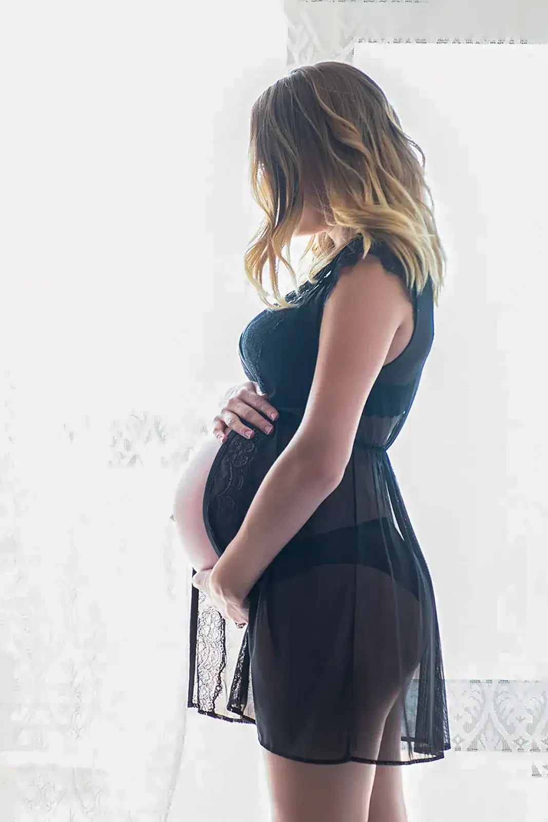 Soft Lingerie Maternity Portrait Pregnant woman in a sheer black maternity lingerie dress photographed in soft window light